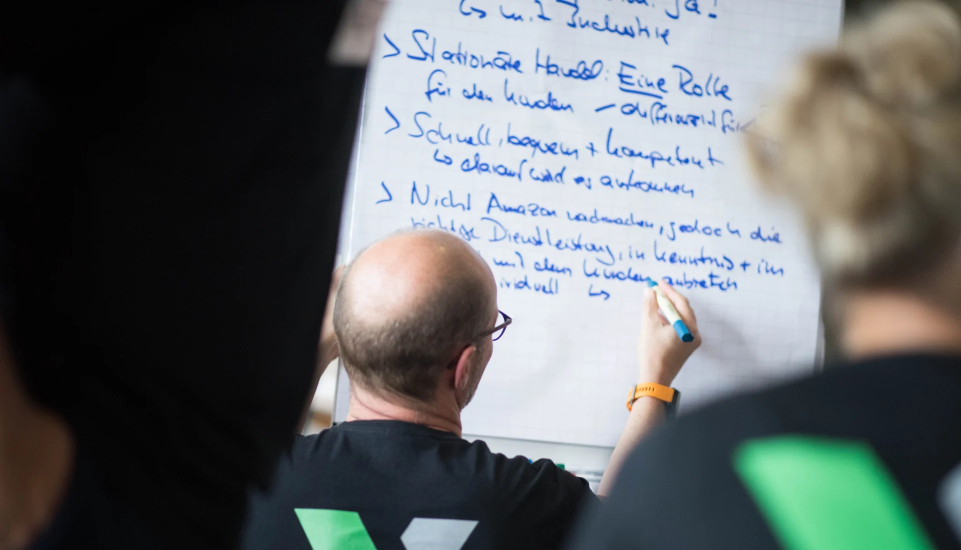 Participant writing fields of action on a flip chart during a strategy workshop